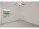 Bright bedroom features a ceiling fan, neutral carpet, white walls, and a window overlooking the backyard at 156 Harmony Trl, Broadway, NC 27505