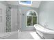 Bright bathroom featuring skylight, soaking tub, glass-enclosed shower, and large window at 1901 White Oak Rd, Raleigh, NC 27608