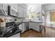 Well-lit kitchen features stainless steel appliances, white cabinetry, and elegant black countertops at 1901 White Oak Rd, Raleigh, NC 27608