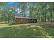 Brick house in a backyard featuring a lush, green lawn with mature trees, offering privacy and natural beauty at 2005 Messer Rd, Raleigh, NC 27603