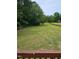 Expansive backyard featuring mature trees, a wooden fence, and a charming play area at 216 Edgecombe Dr, Spring Lake, NC 28390