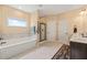 Bathroom featuring a soaking tub, glass-enclosed shower, double vanity, and neutral tile flooring at 216 Tarkenton Ct, Clayton, NC 27527