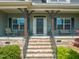Inviting front porch with a charming entrance featuring decorative pillars, brick stairs, and wrought iron railings at 216 Tarkenton Ct, Clayton, NC 27527