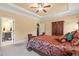 Comfortable main bedroom showing a tray ceiling, ceiling fan, carpeting, and a view to the bathroom at 216 Tarkenton Ct, Clayton, NC 27527