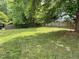Spacious backyard featuring a lush green lawn, mature trees, and a wooden fence for privacy at 2208 Fieldmont Ct, Raleigh, NC 27614