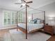 Bright bedroom featuring a four-poster bed, hardwood floors, and large windows for natural light at 224 Midden Way, Holly Springs, NC 27540