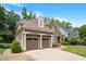 Side view of a two-story home featuring a two-car garage, stone accents, and a well-maintained lawn at 224 Midden Way, Holly Springs, NC 27540