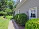 Side exterior view of a well-maintained house with a manicured lawn, lush bushes, and a charming brick walkway at 224 Midden Way, Holly Springs, NC 27540