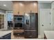 A modern kitchen includes a stainless steel refrigerator and built-in double oven at 224 Midden Way, Holly Springs, NC 27540