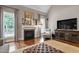 Cozy living room featuring a fireplace, hardwood floors, and large windows that provide plenty of natural light at 224 Midden Way, Holly Springs, NC 27540