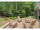 Relaxing stone patio featuring comfortable Adirondack chairs surrounded by lush trees, perfect for outdoor gatherings and relaxation at 224 Midden Way, Holly Springs, NC 27540