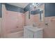 Bathroom featuring pink tiling, a shower-tub combo, unique light fixtures, and a vanity sink with storage at 722 Baker St, Oxford, NC 27565