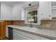 Bright kitchen sink area with tiled backsplash, stainless steel appliances, and a large window overlooking the backyard at 722 Baker St, Oxford, NC 27565