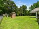 Expansive backyard featuring lush green grass, mature trees, and a charming brick outbuilding at 8917 Thompson Mill Rd, Wake Forest, NC 27587