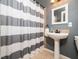 Bathroom with a pedestal sink, striped shower curtain, and neutral-toned tiles at 8917 Thompson Mill Rd, Wake Forest, NC 27587