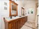 A bathroom featuring dual sinks, granite countertops, a large framed mirror, and wood cabinetry at 8917 Thompson Mill Rd, Wake Forest, NC 27587