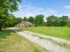 View of home and gravel driveway with a sprawling green lawn leading to a secluded and private property at 8917 Thompson Mill Rd, Wake Forest, NC 27587