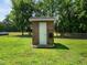 A brick shed with a single door, hose caddy, and well-maintained lawn in the backyard at 8917 Thompson Mill Rd, Wake Forest, NC 27587