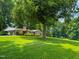 Well-maintained brick home with a carport, landscaped yard, and mature trees at 9455 Boston Rd, Roxboro, NC 27574