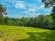 Expansive green field with a clear blue sky and mature trees, creating a serene setting at 9455 Boston Rd, Roxboro, NC 27574