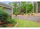 Serene backyard featuring a stone retaining wall, lush greenery, and mature trees at 958 Bay Bouquet Ln, Apex, NC 27523