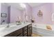 Main bathroom features a soaking tub and a double sink vanity, complemented by a stylish mirror and decorative shelves at 100 Beaconwood Ln, Holly Springs, NC 27540