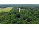 An aerial view captures the expansive green landscape, showcasing the property's proximity to both forested areas and open fields at 1006 Oxford Ridge Rd, Wake Forest, NC 27587