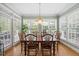 Sunlit dining area features large windows, hardwood floors, a chandelier, and views of the lush outdoors at 1009 Bentham Dr, Raleigh, NC 27614