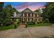 Elegant brick home with a manicured lawn, mature trees, and a circular driveway at sunset at 1009 Bentham Dr, Raleigh, NC 27614
