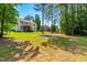 Lush backyard with a fire pit, mature trees, hammock, and partial view of the home's exterior at 1054 Contender Dr, Clayton, NC 27520