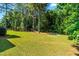 Expansive backyard with lush lawn, mature trees, playground, hammock, and a fire pit area for outdoor enjoyment at 1054 Contender Dr, Clayton, NC 27520