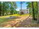 Spacious backyard featuring a fire pit, green grass, mature trees and a distant hammock at 1054 Contender Dr, Clayton, NC 27520