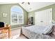 Cozy bedroom featuring a large window, a bed with patterned bedding, and green walls at 1054 Contender Dr, Clayton, NC 27520