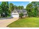 Well-maintained two-story home with an attached garage, long driveway, lush lawn, and mature trees adding to its curb appeal at 1054 Contender Dr, Clayton, NC 27520
