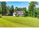 Well-maintained two-story house with a lush green lawn, mature trees, and a welcoming front porch at 1054 Contender Dr, Clayton, NC 27520