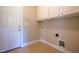 Neutral laundry room with upper cabinets, tile floors and a white door at 109 Lake Point Dr, Clayton, NC 27527