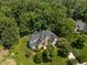 Stunning home nestled among mature trees featuring a stone facade and well manicured yard at 109 San Juan Dr, Chapel Hill, NC 27514