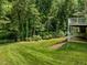 Lush backyard with mature trees, a manicured lawn, and a shaded patio for outdoor relaxation at 109 San Juan Dr, Chapel Hill, NC 27514