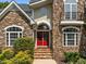 Stunning front entrance showcasing stone architecture, a red front door, and manicured shrubs at 109 San Juan Dr, Chapel Hill, NC 27514