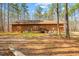 Exterior view of a log cabin style home with a backyard patio surrounded by trees at 1101 Dimmocks Mill Rd, Hillsborough, NC 27278