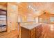 Expansive living room with wood-paneled walls and floors, a stone fireplace, and a kitchen view at 1101 Dimmocks Mill Rd, Hillsborough, NC 27278