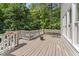 A sun-drenched wooden deck with a seating area surrounded by lush trees at 111 Canberra Ct, Cary, NC 27513
