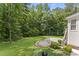 Backyard features a circular brick patio, lush landscaping, and mature trees for privacy at 111 Canberra Ct, Cary, NC 27513