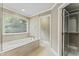Relaxing bathroom with a soaking tub, tiled walls, natural light, and a convenient closet at 111 Canberra Ct, Cary, NC 27513