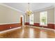 A dining room with hardwood floors, wainscoting, a chandelier, and bright natural light at 111 Canberra Ct, Cary, NC 27513