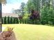 Private backyard featuring a well-maintained lawn, mature trees, and landscaping, offering a serene outdoor space at 1205 Capstone Dr, Durham, NC 27713