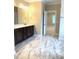 Bathroom with marble tile flooring, dark wood cabinets, dual sinks and an adjacent open room at 1205 Capstone Dr, Durham, NC 27713