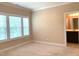 Bright bedroom featuring neutral carpet, trim, paint, and an open doorway to an ensuite bathroom at 1205 Capstone Dr, Durham, NC 27713