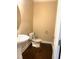 Cozy half-bathroom featuring a pedestal sink, white fixtures, and dark hardwood flooring at 1205 Capstone Dr, Durham, NC 27713