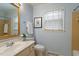 Cozy bathroom featuring a framed mirror, single vanity, and a window for natural light at 1317 Swallow Dr, Raleigh, NC 27606